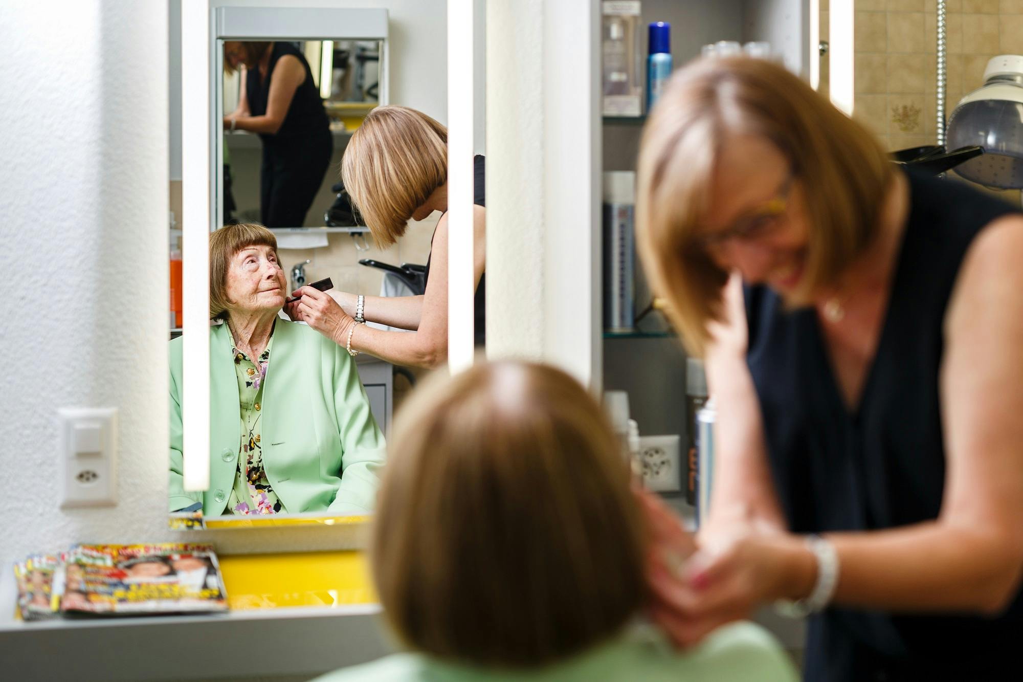 Ältere Frau bekommt im Friseursalon Make-up aufgetragen, Spiegelbild.